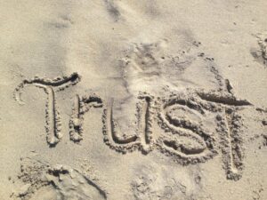 Das Wort "Trust" in den Sand gezeichnet